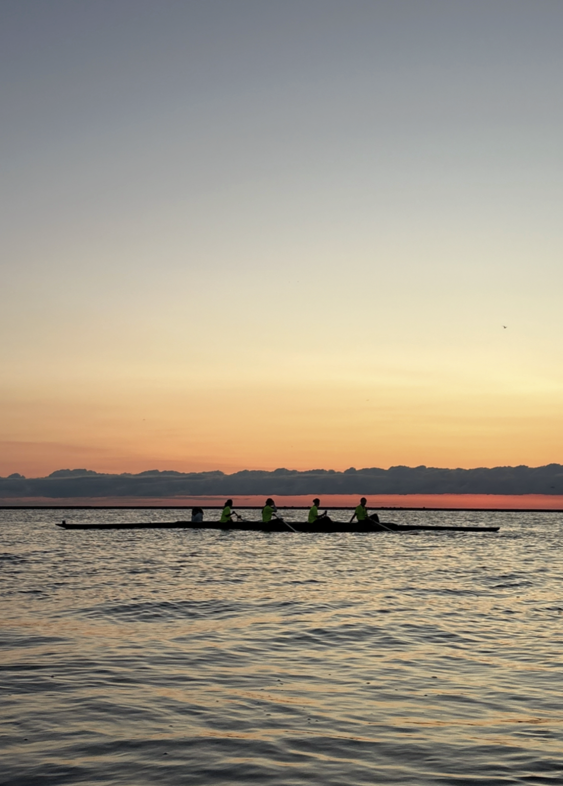 A Marquette four rows on Lake Michigan at sunrise, downtown Milwaukee behind them.